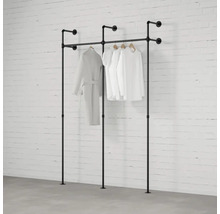 Volně stojící věšáky na šaty z trubek s oblečením před cihlovou zdí