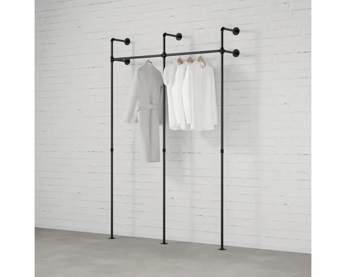 Volně stojící věšáky na šaty z trubek s oblečením před cihlovou zdí