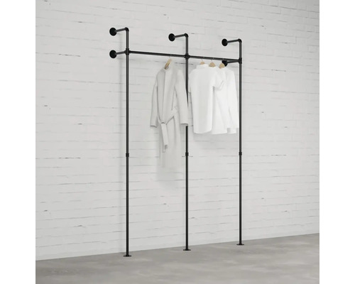 Černý věšák na oblečení s oblečením před cihlovou zdí