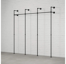 Černý kovový věšák na oblečení z trubek před bílou cihlovou zdí