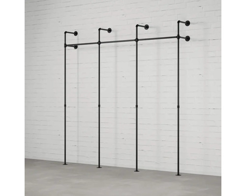 Černý kovový věšák na oblečení z trubek před bílou cihlovou zdí