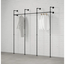 Černý trubkový systém na šaty se zavěšeným oblečením před cihlovou zdí