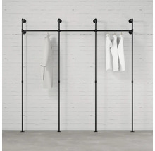 Černý věšák na oblečení z trubek s bílým oblečením na cihlové zdi