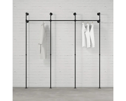 Černý věšák na oblečení z trubek s bílým oblečením na cihlové zdi