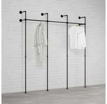 Černá kombinace šatního stojanu z trubek před bílou cihlovou zdí se zavěšeným oblečením.