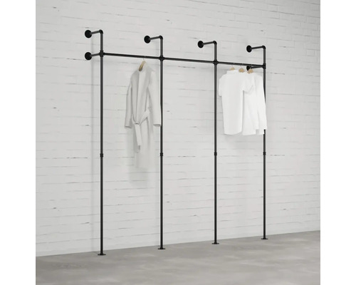 Černá kombinace šatního stojanu z trubek před bílou cihlovou zdí se zavěšeným oblečením.