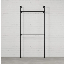 Černý kovový věšák na šaty před cihlovou zdí