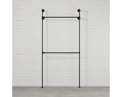 Černý kovový věšák na šaty před cihlovou zdí