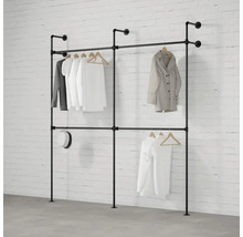 Věšák na šaty z trubek se zavěšeným oblečením před cihlovou zdí