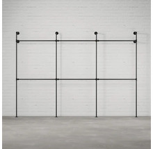 Černý trubkový systém věšáku na šaty před cihlovou zdí