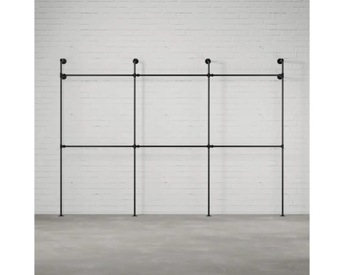 Černý trubkový systém věšáku na šaty před cihlovou zdí