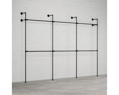 Černý ocelový trubkový šatní systém před cihlovou zdí