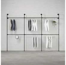 Černý kovový trubkový věšák na šaty s oblečením před cihlovou zdí