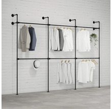 Volně stojící systém věšáků na šaty s několika kusy oblečení, kloboukem a rostlinou