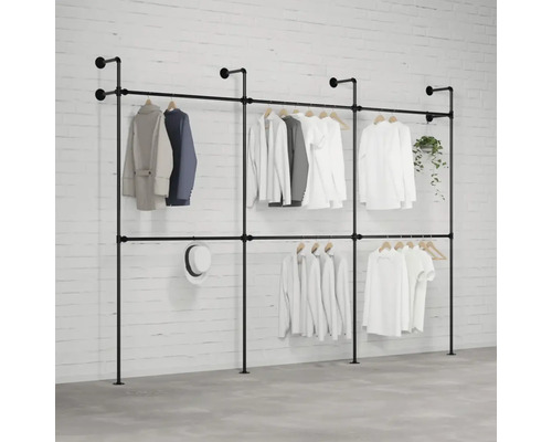 Volně stojící systém věšáků na šaty s několika kusy oblečení, kloboukem a rostlinou