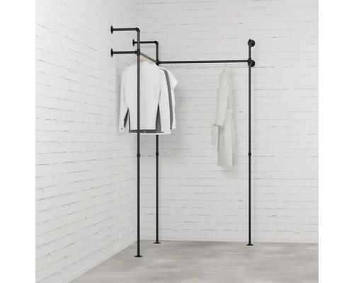 Černý věšák na oblečení z kovových trubek s oblečením před cihlovou zdí