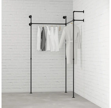 Černý kovový trubkový věšák na oblečení s oblečením před cihlovou zdí