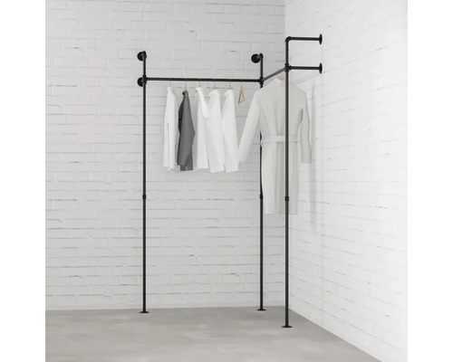 Černý kovový trubkový věšák na oblečení s oblečením před cihlovou zdí
