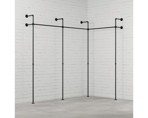 Věšák na šaty z trubek v rohovém pokoji před cihlovou zdí