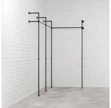 Černá konstrukce věšáku na šaty z trubek před cihlovou zdí