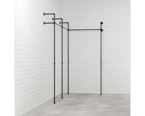 Černá konstrukce věšáku na šaty z trubek před cihlovou zdí