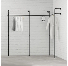 Černý šatní systém s oblečením před bílou cihlovou zdí