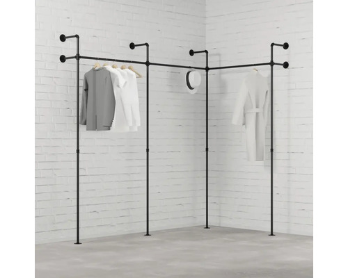 Rohový věšák na šaty z trubek s oblečením před cihlovou zdí