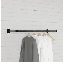 Černá šatní tyč s oblečením na cihlové zdi