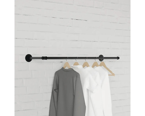 Černá šatní tyč s oblečením na cihlové zdi