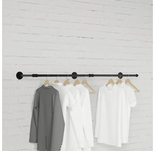 Nástěnný věšák s oblečením visícím před cihlovou zdí