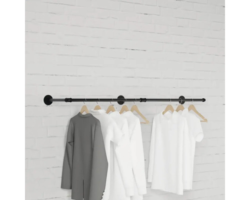 Nástěnný věšák s oblečením visícím před cihlovou zdí