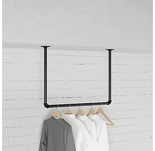 Stojan na šaty z ocelových trubek s visícím oblečením před cihlovou zdí