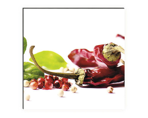 Chilli papričky, zelené listy a různá zrnka pepře leží na světlém povrchu.