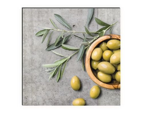 Zátiší s olivami v dřevěné misce a olivovou ratolestí na betonovém pozadí
