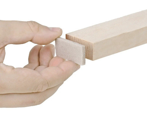 Osoba připevňuje plstěný kluzák na kus dřeva.