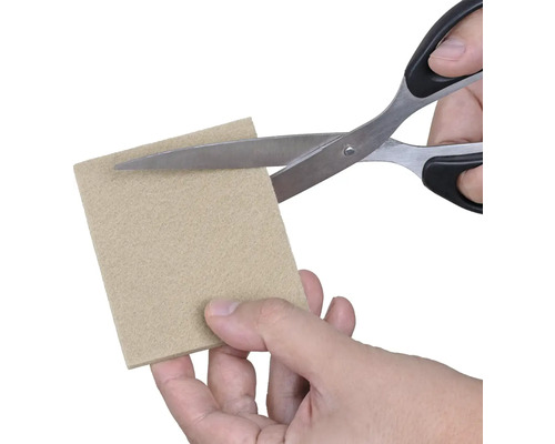 Osoba stříhá kus plsti nůžkami.