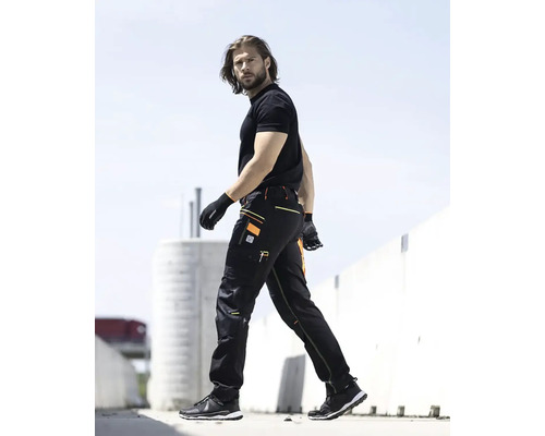 Muž v pracovních kalhotách a rukavicích venku