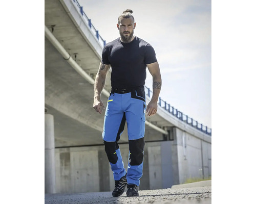 Muž má na sobě modré pracovní kalhoty s kapsami na kolenou.