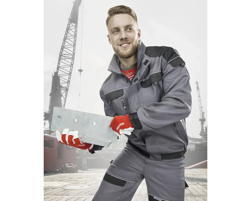 Muž v pracovním oblečení s kovovým nosníkem před jeřábem