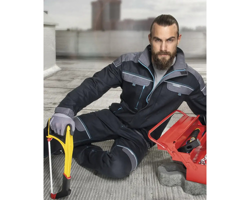 Řemeslník s pracovními kalhotami, ocaskou pilou a kufříkem na nářadí na staveništi.