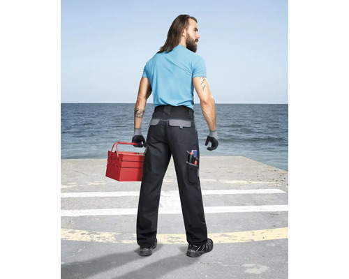 Muž s kufříkem na nářadí a pracovními kalhotami s kapsami