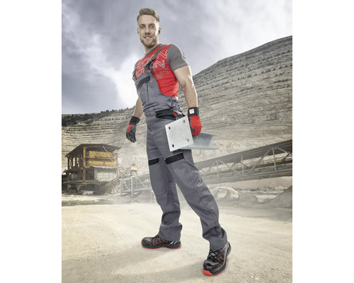 Muž v pracovním oděvu s kovovou deskou v kamenolomu