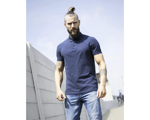 Muž s plnovousem a drdolem nosí polokošili a džíny