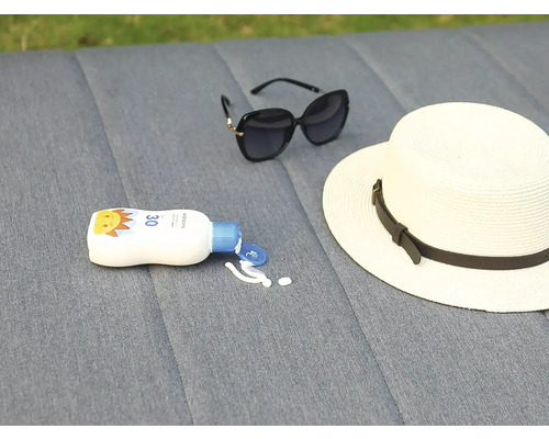 Krém na opalování, klobouk a sluneční brýle leží na šedém pozadí.