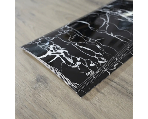 Černé mramorové samolepicí dlaždice na dřevěné podlaze.