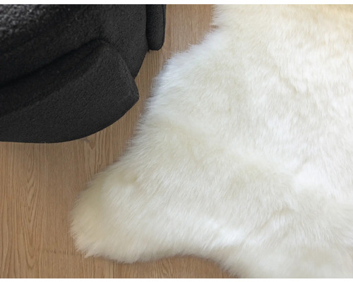 Bílý koberec z umělé kožešiny vedle křesla