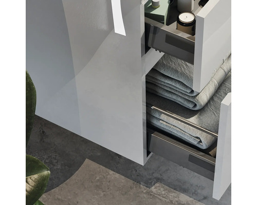 Detailní pohled na koupelnovou skříňku s otevřenými zásuvkami a ručníky