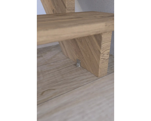 Detailní pohled na dřevěné schodiště s kovovým úhelníkem pro upevnění.