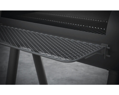 Detailní pohled na gril na dřevěné uhlí s odkládací mřížkou.