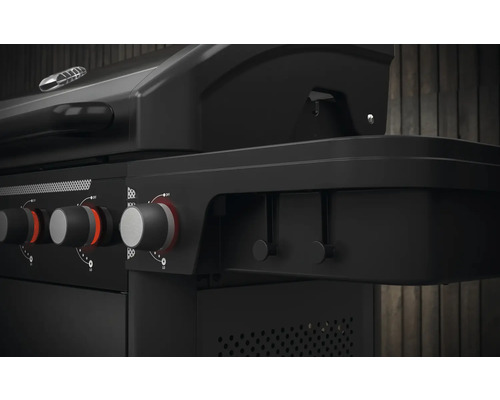 Detailní záběr černého plynového grilu s otočnými knoflíky pro regulaci teploty.